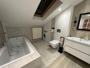 een badkamer met een bad, een wastafel en een toilet bij Apartament Nidzica Rzemieślnicza 4 in Nidzica