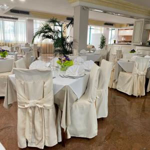 un comedor con mesas blancas y sillas blancas en Porto Cesareo Hotel, en Porto Cesareo