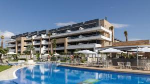 un hotel con una piscina con sillas y sombrillas en Luxury apartment in Flamenca Village/Orihuela Costa, en Orihuela Costa