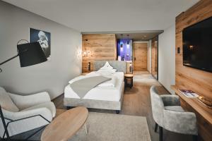 a hotel room with a bed and two chairs at Cyprianerhof Dolomit Resort in Tires