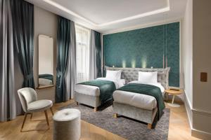 a hotel room with two beds and a chair at Mamaison Hotel Riverside Prague in Prague