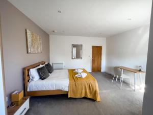 a bedroom with a bed with a yellow blanket on it at The Crows Nest by Paymán Club in Lowestoft