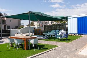 a patio with a table and chairs and a green umbrella at Kite Basecamp Langebaan in Langebaan