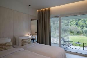 Kechria的住宿－OHLIVE Beach Villa Skiathos，一间卧室设有一张床和一个美景阳台