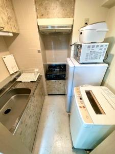 a small kitchen with a refrigerator and a microwave at 2-2札幌駅徒歩7分の好立地Service Apartment SAPPORO札幌ステーション綺麗な部屋 in Kita-rokujō