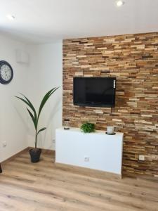 un salon avec une télévision sur un mur en briques dans l'établissement La P'tite Bas-Rivière, à Blois