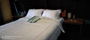 1 dormitorio con 1 cama con sábanas y almohadas blancas en D'kailash Retreat, en Singaraja