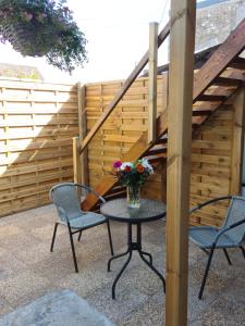un patio avec deux chaises et une table avec un vase de fleurs dans l'établissement La P'tite Bas-Rivière, à Blois