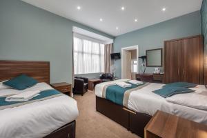 a hotel room with two beds and a desk at King Solomon Hotel- Golders Green in London