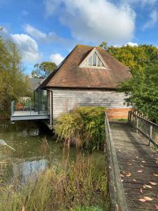 a house with a bridge over a body of water at Weavers Rest in Biddenden