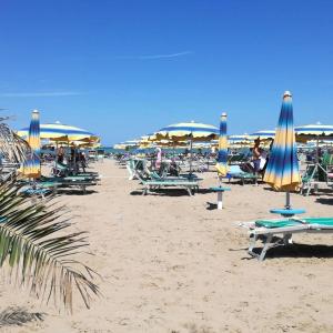 um grupo de cadeiras e guarda-sóis numa praia em Appartamento Minerva em Rimini
