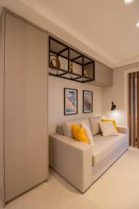 1 dormitorio con sofá blanco y almohadas amarillas en Unique Studio - GRU, en Guarulhos