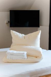 einen Stapel Kissen auf einem Bett mit einem TV in der Unterkunft Ostsee - Reetdachhaus Nr 2 "SÜDSTRANDHUS" im Strand Resort in Heiligenhafen