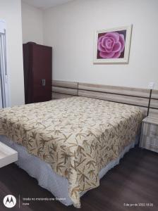 een bed in een slaapkamer met een bloem aan de muur bij Lindo Apartamento de Frente para o mar in Caraguatatuba