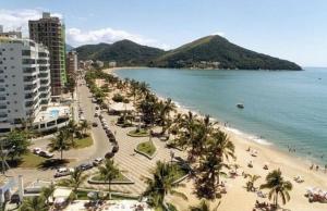 een uitzicht op een strand met palmbomen en de oceaan bij Lindo Apartamento de Frente para o mar in Caraguatatuba