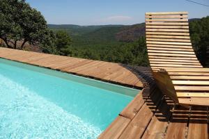 a pool with a chair sitting on a wooden deck at Les Combres, gîte nature avec piscine in Malbosc