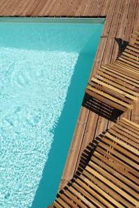 a pool of water with two wooden benches next to it at Les Combres, gîte nature avec piscine in Malbosc