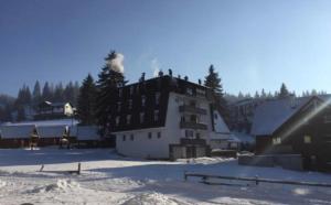 un gran edificio en la nieve con humo. en Apartmani Šišava apt "HARMONY" Vlašić, en Vlašić