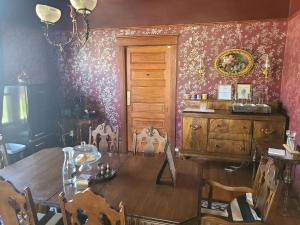 a dining room with a wooden table and a wall with flowers at The Bissing House in Hays