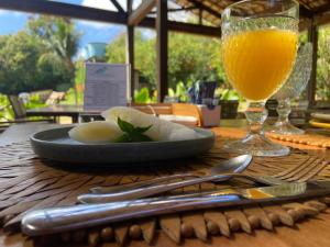 a table with a plate of food and a glass of orange juice at Pousada Simpatia da Ilha in Fernando de Noronha