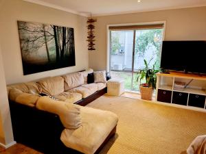 uma sala de estar com um sofá e uma televisão de ecrã plano em Cozy Beachcomber @Smith's Beach em Smiths Beach