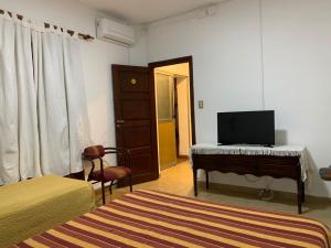 Dormitorio con cama, escritorio y TV en Hotel Residencial España en Salta