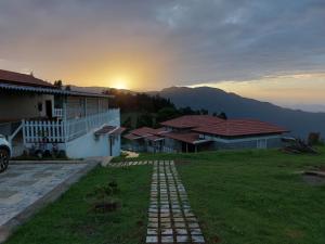 a view of a house with the sunset in the background at Tranqville Resorts in Ooty