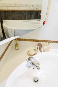 ein Waschbecken mit einem Spiegel und einer Badewanne in der Unterkunft Captain Buda Apartment in Budapest