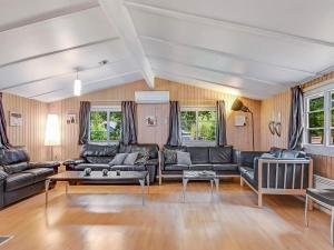 Øster Vrøgumにある8 person holiday home in Oksb lの黒革の家具と木製の壁が備わるリビングルーム