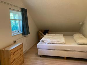 a small bedroom with a bed and a window at Karekiet 42 in Oudemirdum