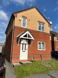 ein Backsteinhaus mit einer weißen Tür und einer Uhr in der Unterkunft 3 bedroom house with parking in Manchester