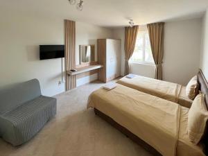 een hotelkamer met 2 bedden en een stoel bij Guest Houses Kapatovo / Къщи за гости КАПАТОВО 