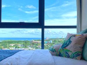 a bedroom with a large window looking out at the ocean at Mactan Newtown - New Modern Condo with Ocean View in Mactan