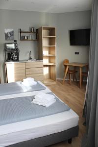 a room with two beds and a kitchen with a table at Novitel Apartements Heimstetten in Kirchheim