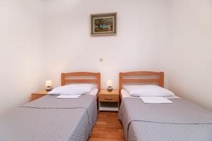 two beds in a small room with two lamps at Jadranovo Dunja in Jadranovo