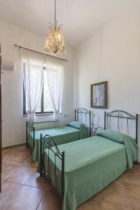 トッレ・サンタ・スザンナにあるMasseria Bellamarinaのシャンデリア付きの客室内の緑色のベッド2台