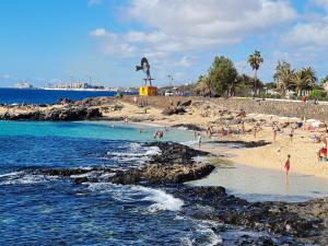 grupa ludzi na plaży z posągiem w obiekcie Cozy Waterman beach house w Costa Teguise