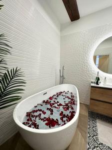 uma casa de banho com uma banheira branca cheia de flores vermelhas em Le Lamartine em Mâcon