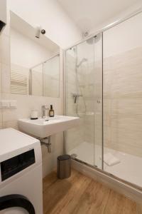ein weißes Bad mit einem Waschbecken und einer Dusche in der Unterkunft Dietrich Apartment I levestate in Wien