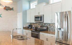 a kitchen with white cabinets and a stainless steel refrigerator at Turtle Paradise in Port Aransas