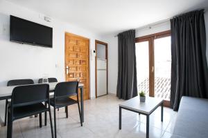 a living room with a table and chairs and a television at L&G Apartamentos in Benidorm