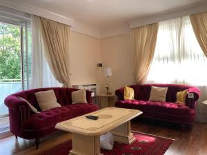 a living room with two red couches and a coffee table at Lovely 3 bedroom apartment in London