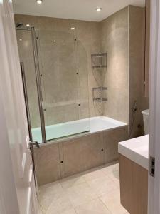 a bathroom with a shower and a tub and a sink at Lovely 3 bedroom apartment in London