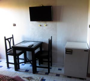 einem Esstisch mit 2 Stühlen und einem TV in der Unterkunft Marrakech Hôtel Résidence in Marrakesch