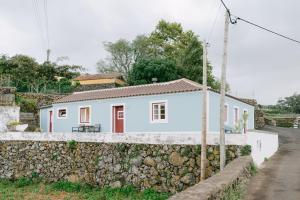 ein weißes Haus hinter einer Steinmauer in der Unterkunft Casa Ver o Mar in São Mateus