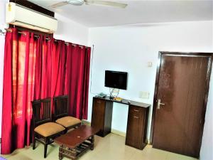 sala de estar con cortinas rojas y TV en Hotel White Palace,Nizamuddin Railway Station, en Nueva Delhi