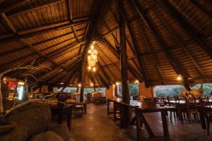 a restaurant with tables and chairs and a large wooden ceiling at Huab Lodge & Bush Spa in Konob Pos