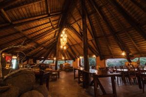 Un restaurante con mesas y sillas y un gran techo de madera. en Huab Lodge & Bush Spa, en Konob Pos