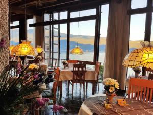 jadalnia ze stołami i krzesłami oraz dużymi oknami w obiekcie Hotel Palazzina w mieście Gargnano