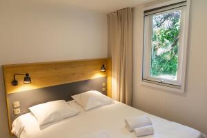 een slaapkamer met een wit bed en een raam bij Camping de l'Orangerie de Lanniron in Quimper